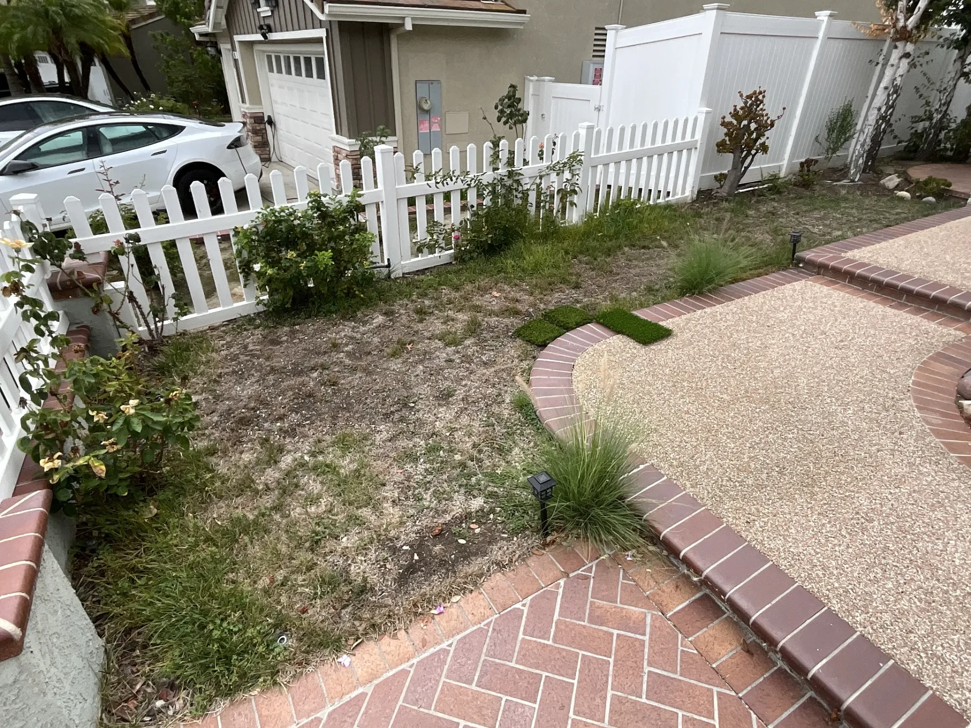 Patchy, thinning natural grass front yard with bare dirt before turf installation