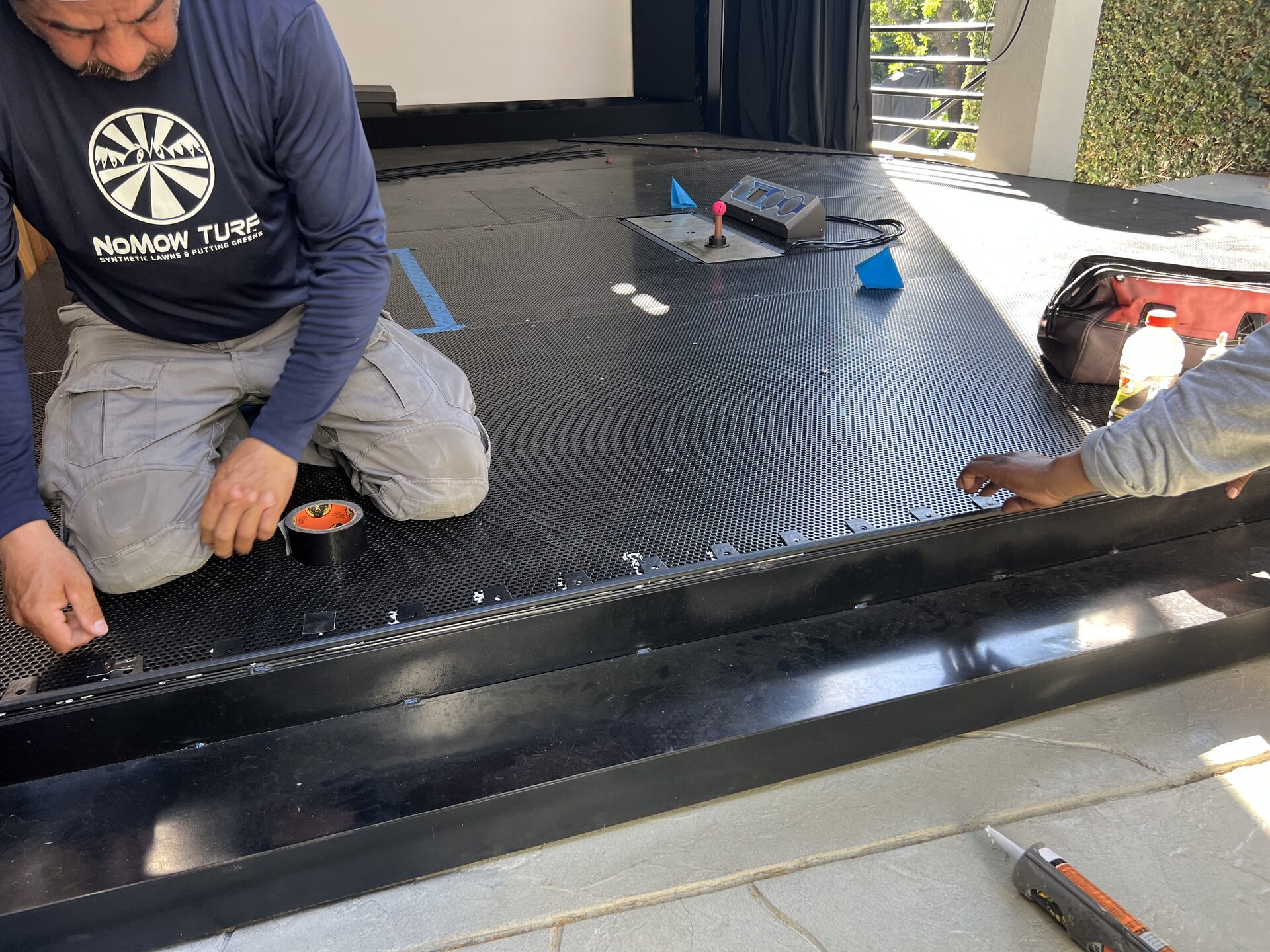 NoMow Turf crew setting the border along the edge of a bare metal simulator platform