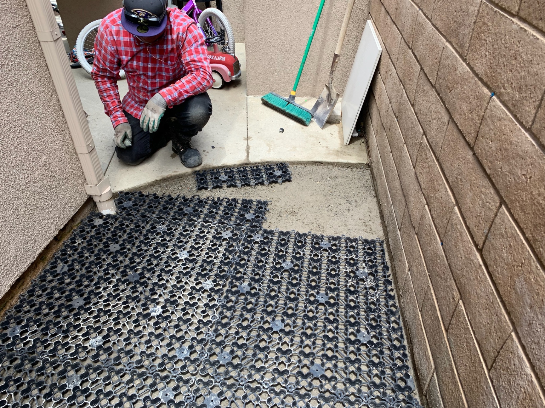 NoMow Turf crew installing the AirDrain K9 drainage grid between hardscape walls