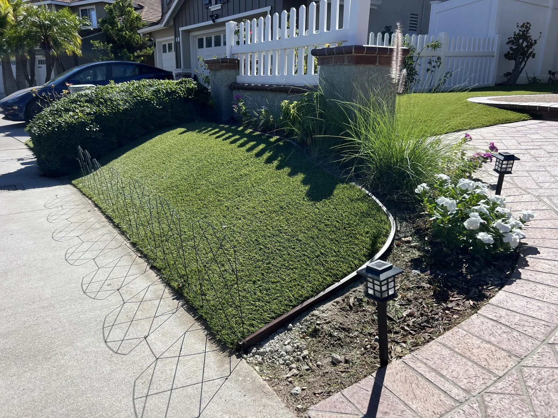 Artificial turf meeting a rock bed and flower planter with a clean edge