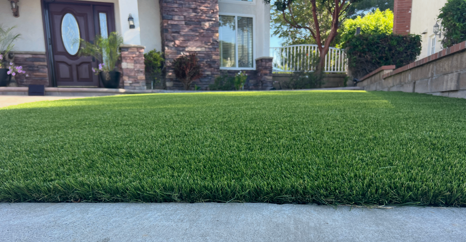 Close-up of a lush, upright artificial turf lawn at a home entryway